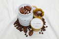 Three containers with coffee beans and a candle on a white background