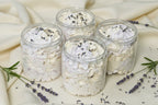 Jars of Sugar Whipped Soap with lavender petals on top, displayed on a cashmere 
surface.