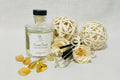 A glass reed diffuser with a black lid and decorative reeds, placed on an old book and a ball of twine.