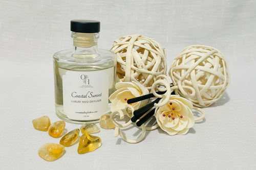 A glass reed diffuser with a black lid and decorative reeds, placed on an old book and a ball of twine.