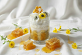 Decorative candle with honeycomb and flowers in a glass container on a white background